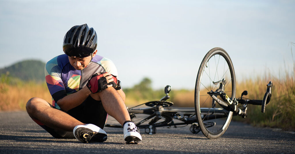 Rennradfahrer hält sich nach Sturz das Knie